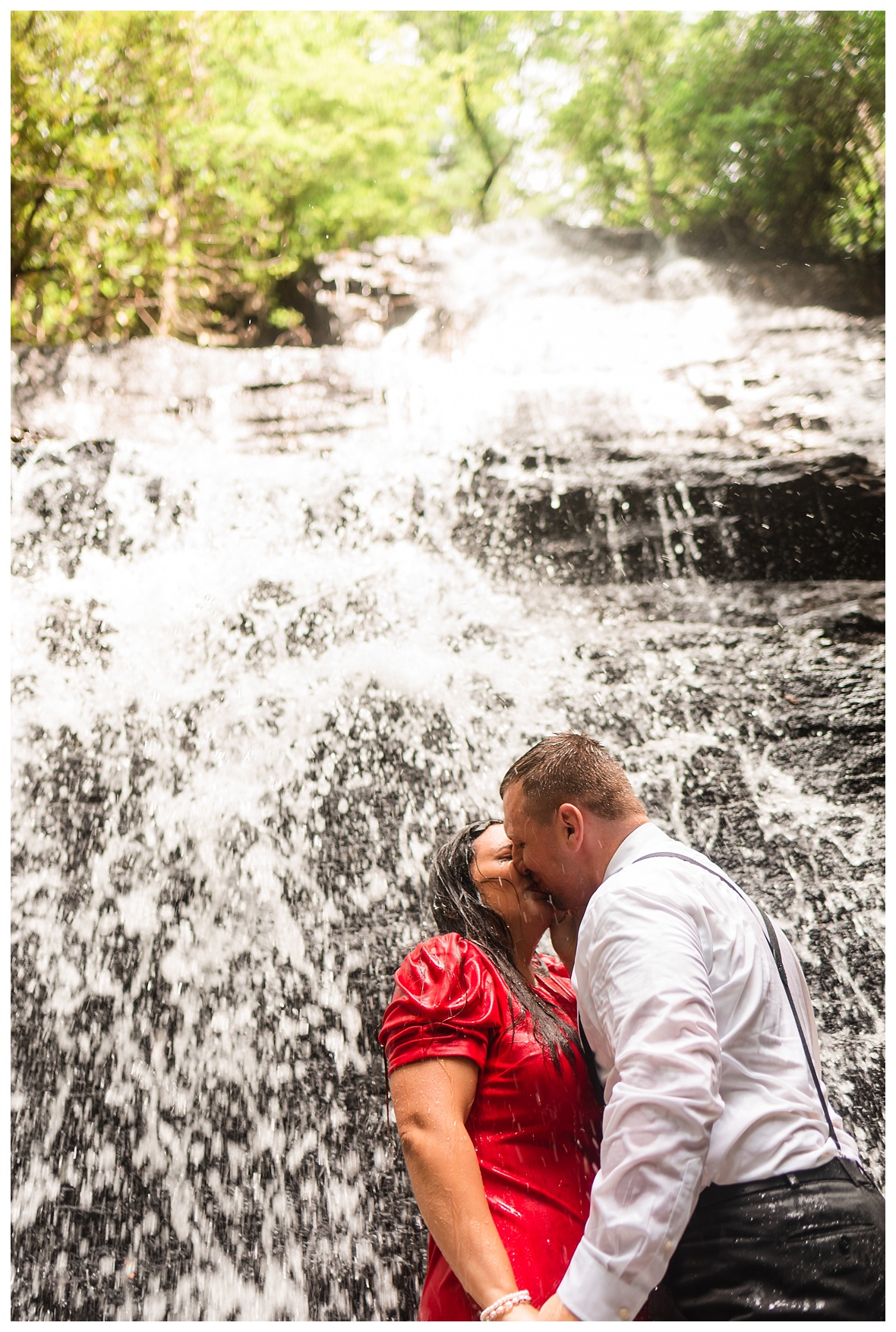 engaged couple kissing under benton waterfall