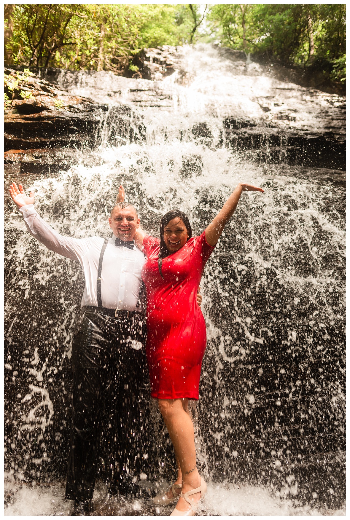 couple cheers under waterfall