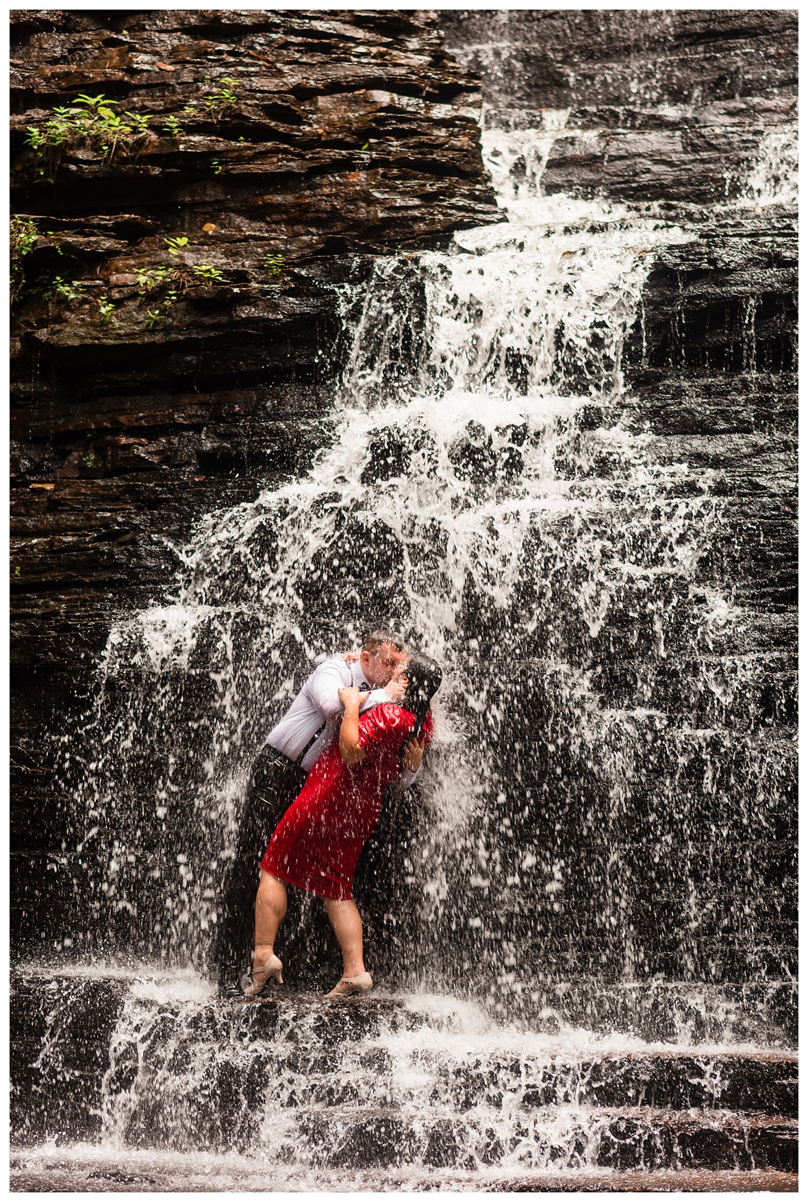 engaged couple kissing under a waterfall