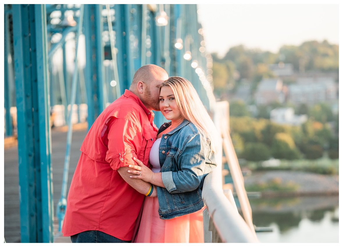 engaged couple embraces on bridge
