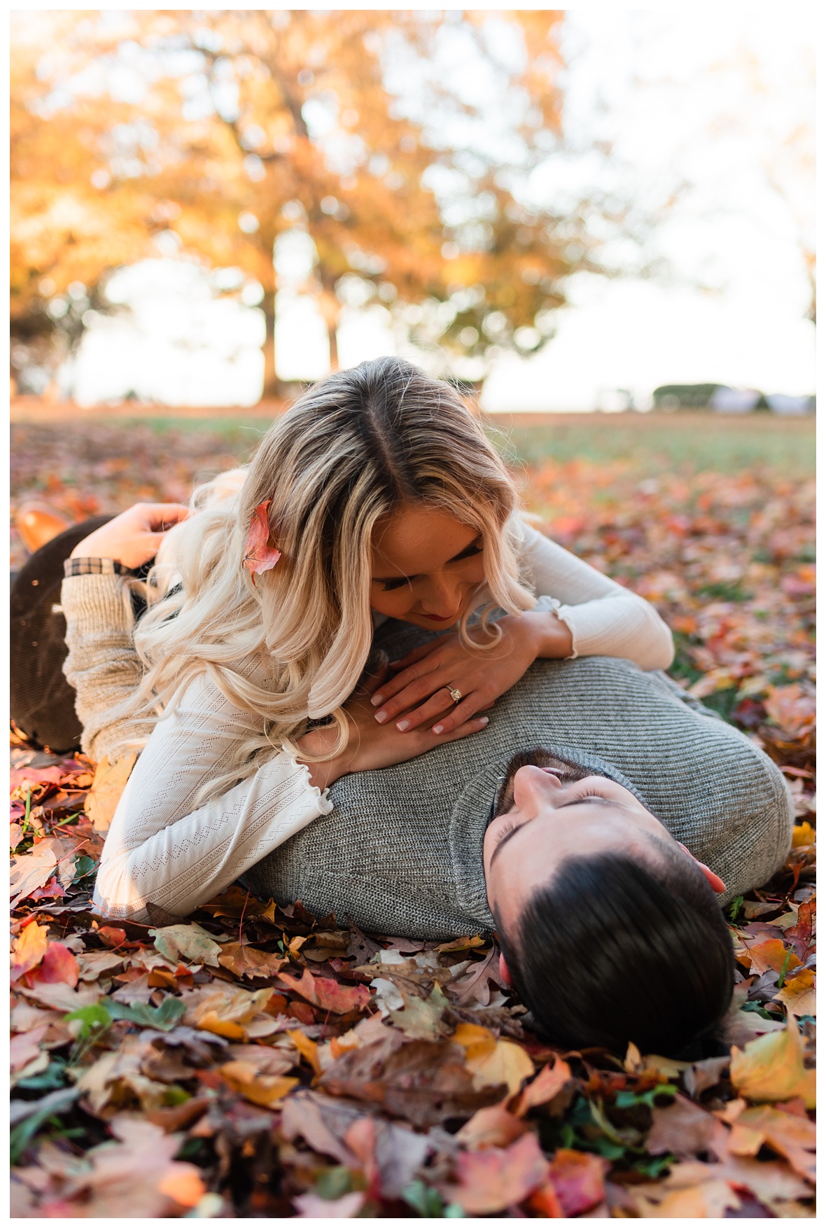 engaged couple rolling in the leaves