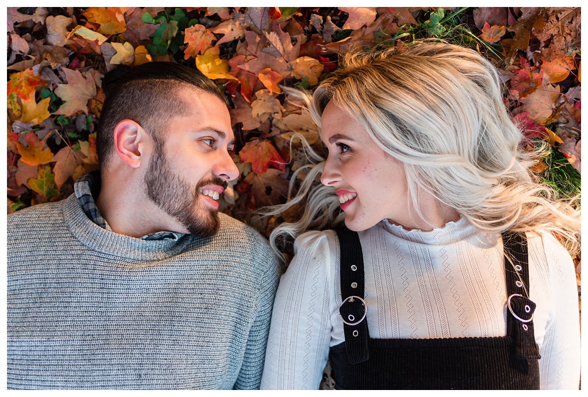 engaged couple rolling in the leaves for fall engagement session